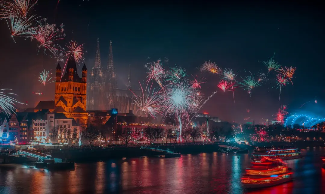 Silvesterfeuerwerk über dem Kölner Dom und beleuchteten Fahrgastschiffen auf dem Rhein bei Nacht