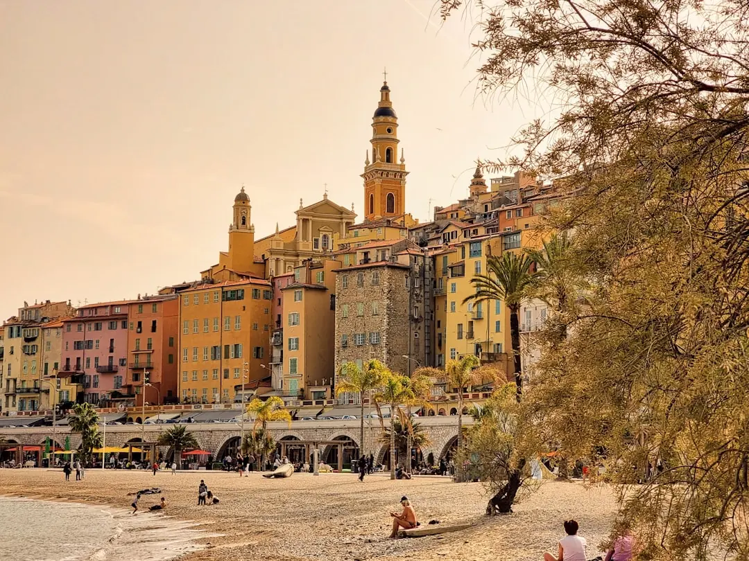 Farbenfrohe Altstadt von Menton an der Côte d’Azur mit Strand und Palmen in warmem Abendlicht