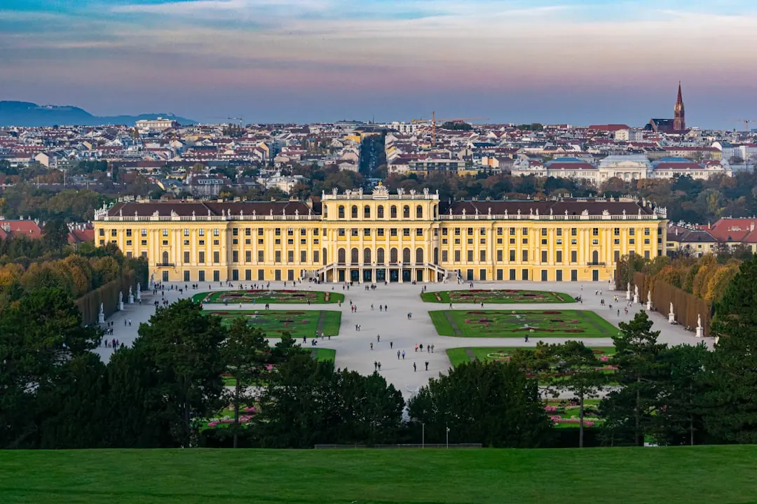Panorama-Blick auf Schloss Schönbrunn in Wien mit den barocken Gartenanlagen vor der herbstlichen Stadtkulisse bei Dämmerung