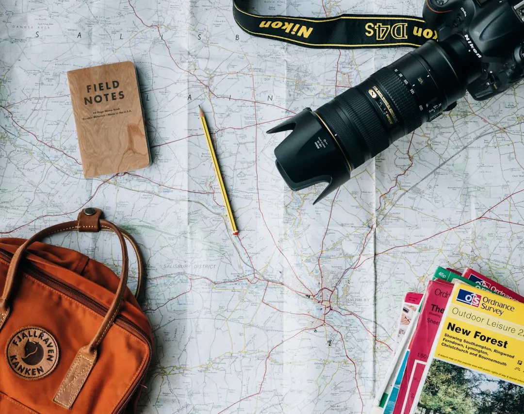 Reiseplanung mit Landkarte, Kamera, Notizbuch und Rucksack in der Draufsicht als Symbol für die Vorbereitung einer Gruppenreise