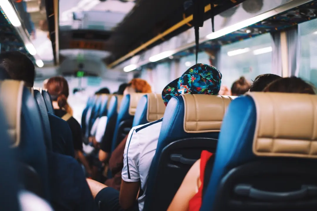 Innenansicht eines Reisebusses mit Fahrgästen, die entspannt in blauen Ledersitzen durch den Gang schauen